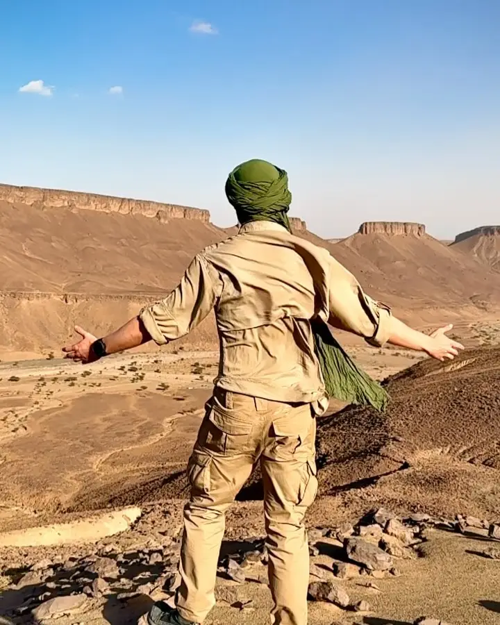 Tim Jambor with outstretched arms above a rocky gorge in the Sahara