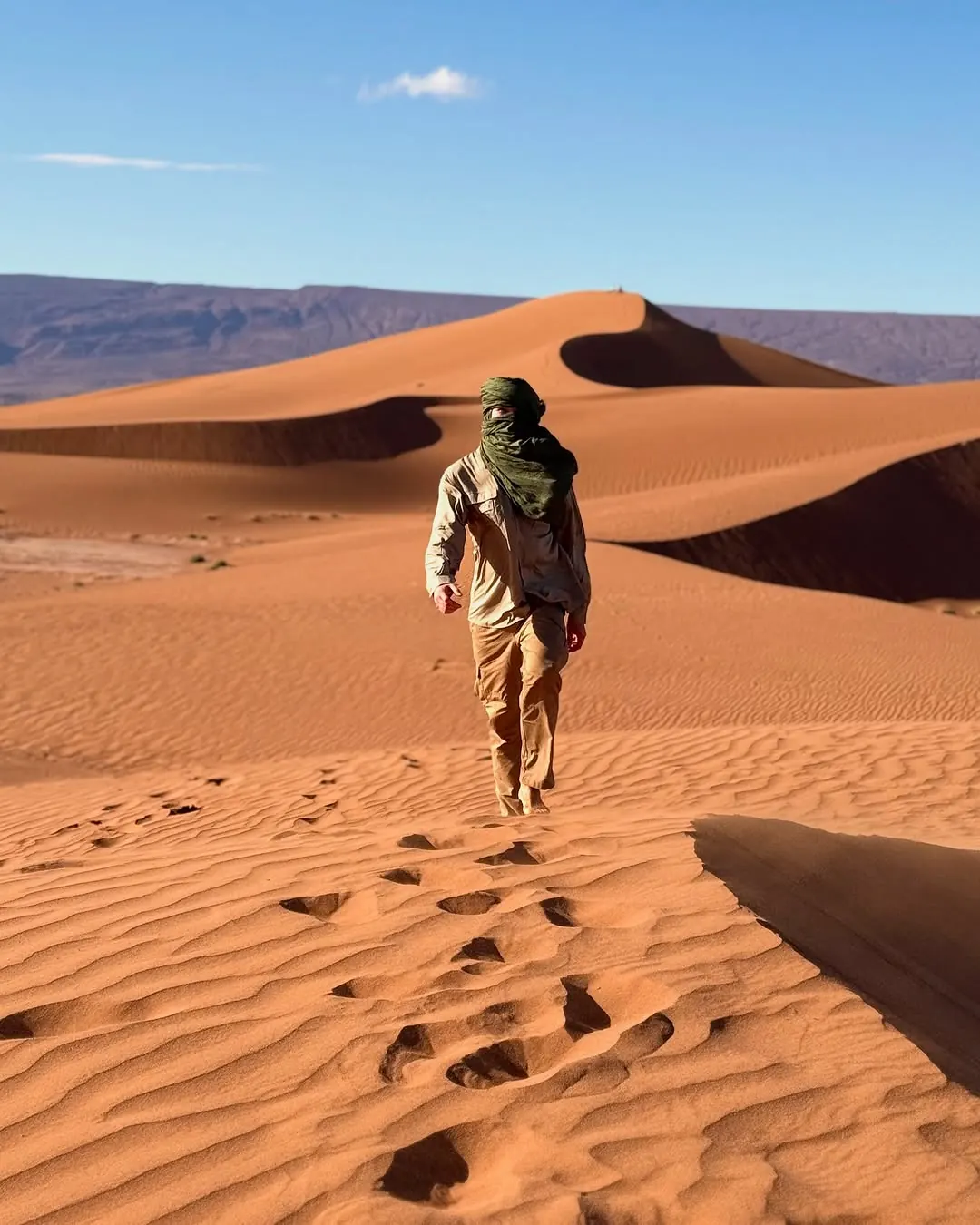 Tim Jambor allein auf einer Düne in der Sahara, hinter ihm seine Fußspuren